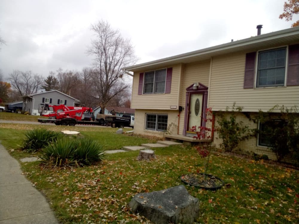 Residential home with truck and trailer in the driveway, surrounded by autumn foliage.